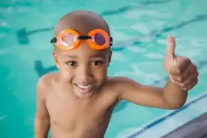 Competitive swimmer smiling in the pool, expressing confidence and joy after a race or practice.